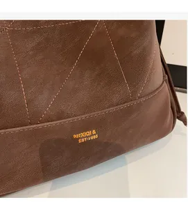 Detail view of brown quilted leather texture with gold logo and precision stitching