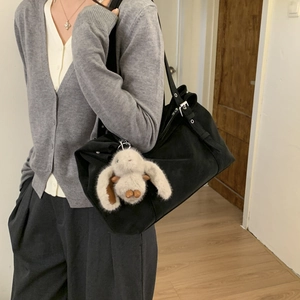 Detail of black tote bag featuring an adjustable shoulder strap and a cute white bunny charm