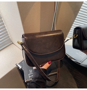 Detail of vintage brown leather handbag with fashion logo and golden metal buckle