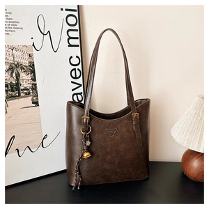 Detail of deep brown leather tote bag with triangle logo and bell charm accessory
