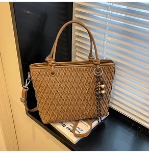 Detail of woven texture on caramel tote bag with knotted handles and beaded tassel