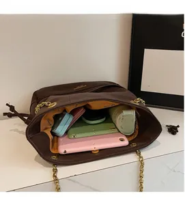 Detail view of large interior capacity of a dark brown quilted tote bag with gold chain