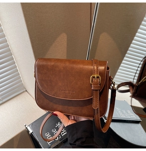 Detail of vintage brown shoulder bag featuring gold metal buckle and leather texture
