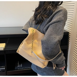 Detail of beige quilted bucket bag with gold chain strap and drawstring closure