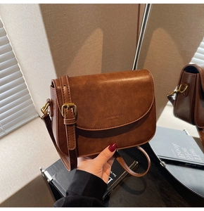 Detail of vintage brown leather handbag with gold buckle and embossed fashion text