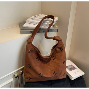 Detail of a brown suede Hobo bag with laser-cut flower patterns and knotted shoulder strap