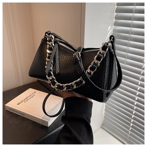Detail of black textured leather bag with chunky silver chain and zip closure