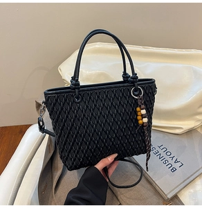 Close-up of black woven bucket bag with beaded tassel and circular top handles