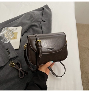 Detail of dark brown leather crossbody bag with embossed logo and extra shoulder strap