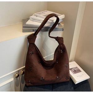 Detail of dark brown faux suede tote bag with laser-cut floral patterns and knotted handle