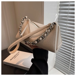 Detail of beige triangle handbag showing lychee leather texture and silver chain strap