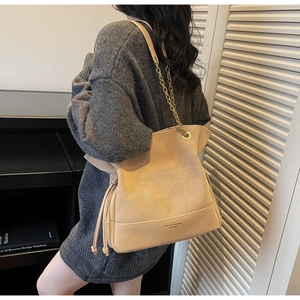 Detail of beige bucket bag with geometric stitching and metal chain shoulder strap