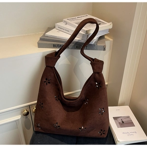 Detail of dark brown suede hobo bag with laser-cut floral pattern and knotted strap