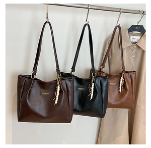 Trois cabas en cuir marron, noir et kaki avec des breloques ethniques en perles de bois