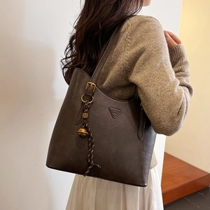 Detail of vintage dark brown faux leather tote bag featuring triangular tag and tassel charm