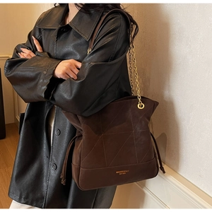 Detailed view of deep brown leather tote with geometric stitching and gold logo