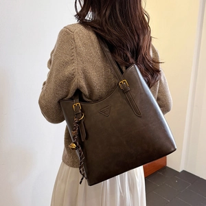 Close-up of vintage dark brown tote bag with decorative knot and gold bell charm