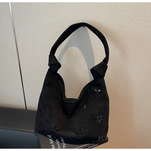 Detail of black suede hobo bag with floral laser-cut patterns and knotted shoulder strap