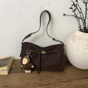 Vintage dark brown matte tote bag with teddy bear pendant on a rustic wooden table