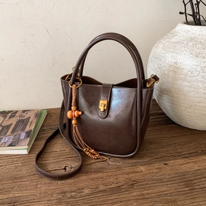 Vue détaillée d'un sac vintage en cuir marron avec boucle dorée et gland en perles