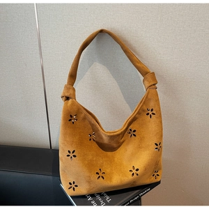 Detail of caramel suede hobo bag with laser-cut floral patterns and knotted strap