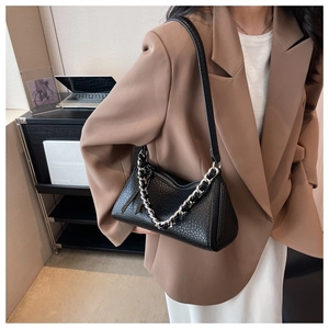 Detail of black lychee texture shoulder bag with decorative silver chain and leather strap