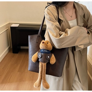 Detailansicht der großen dunkelbraunen Ledertasche mit süßem Bärenanhänger und dünnen Trägern