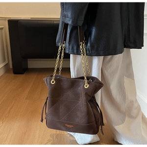 Detail of dark brown vintage bucket bag with geometric stitching and gold chain strap