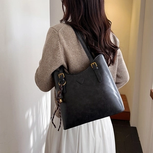 Detail of vintage black bucket bag featuring a gold triangle logo and adjustable strap