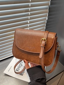 Brown vintage faux leather crossbody bag with gold buckle and chic typography design