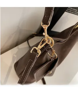 Détail d'un sac en cuir marron foncé avec crochet doré et mini porte-monnaie