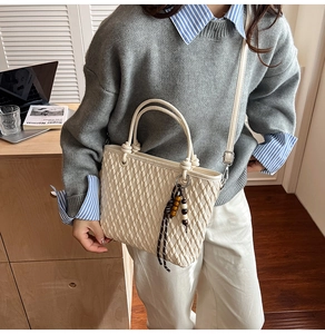 Detail of cream crossbody bag with woven texture and decorative wooden beads