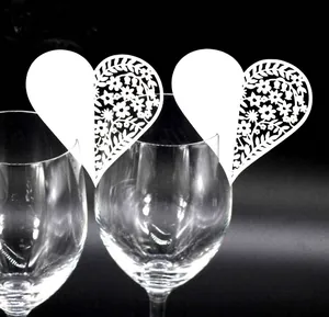 Close-up of white laser-cut heart place cards with intricate floral patterns on a glass