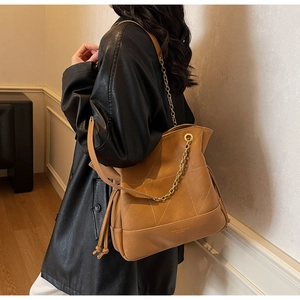 Detail of caramel large bucket bag featuring diamond stitching and gold chain strap