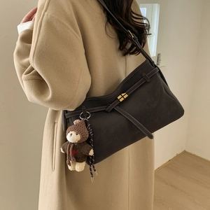 Detail of dark brown tote bag with strap buckle and cute teddy bear plush charm