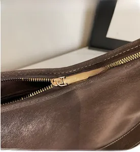 Gros plan détaillé sur la fermeture éclair dorée d'un sac à bandoulière en cuir marron