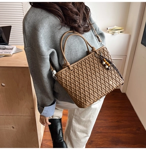 Brown woven leather bucket bag detail with wooden bead charms and long shoulder strap