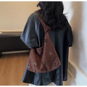 Detail of dark brown shoulder bag with laser-cut floral patterns and knotted strap design