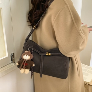 Detail of dark brown nubuck shoulder bag with gold turn-lock and cute bear charm