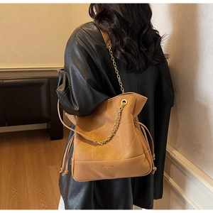 Caramel bucket bag detail showing soft PU leather texture and gold chain link strap