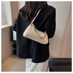 Close-up of cream lychee texture leather bag with bold silver chain and shoulder strap