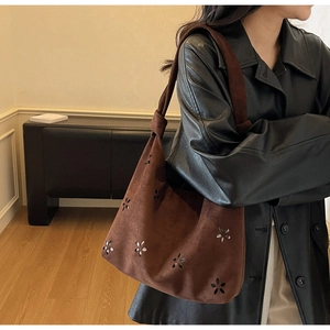 Brown suede tote bag with hollow flower patterns shown in a cozy interior setting