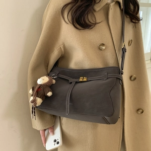Detail of dark grey tote bag with gold swivel lock and cute brown plush bear charm