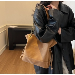 Detail of vintage brown leather bucket bag with contrast stitching and gold chain strap