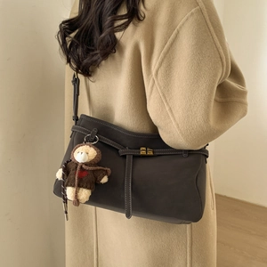 Detail of vintage textured dark brown tote bag with bear charm on a wool coat