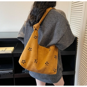 Detail of laser-cut floral patterns and knotted strap on caramel suede tote bag