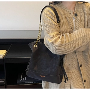 Detail of vintage black bucket bag showing quilted texture, gold chain and brand logo