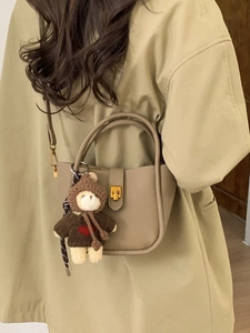 Chic beige textured leather bucket bag with cute teddy bear charm and gold metal lock