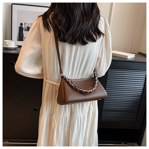 Detail of dark brown lychee textured leather crescent bag with silver chain strap