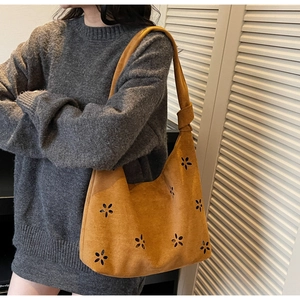 Close-up of mustard yellow suede tote bag featuring laser-cut floral patterns and knotted strap